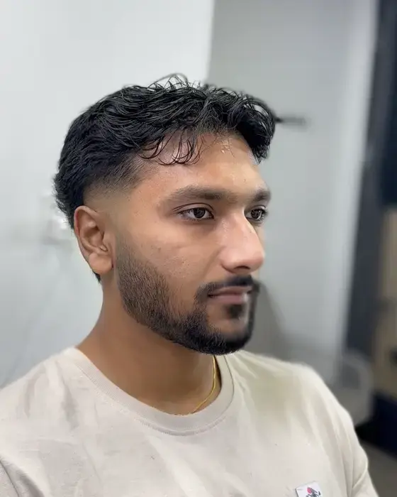 Wavy fringe with a taper fade and neatly trimmed beard
