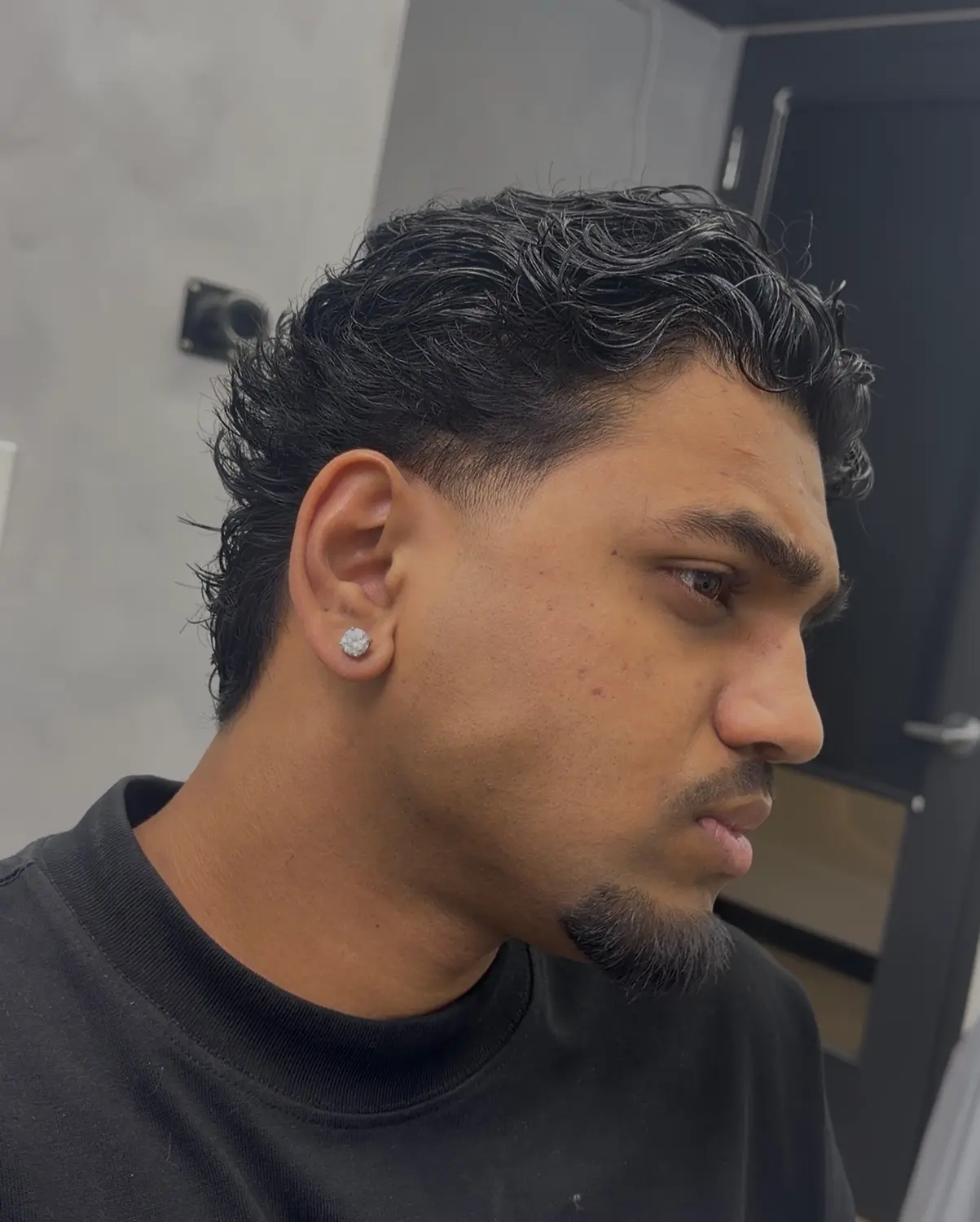 Wavy mullet with a low fade, shown in side profile